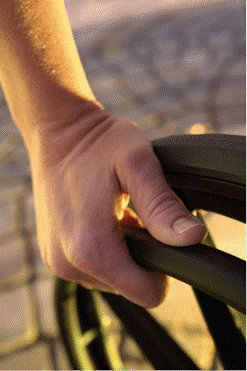 A up close picture of someone's hand on a push bar of their wheelchair.