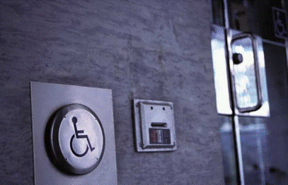 A picture of an handicap push button on a wall for the electric doors.